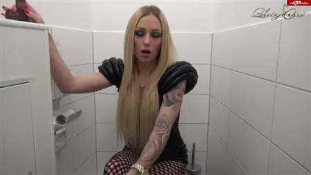 Tätowierte blonde Übungen mit einem Gummimitglied in der Toilette